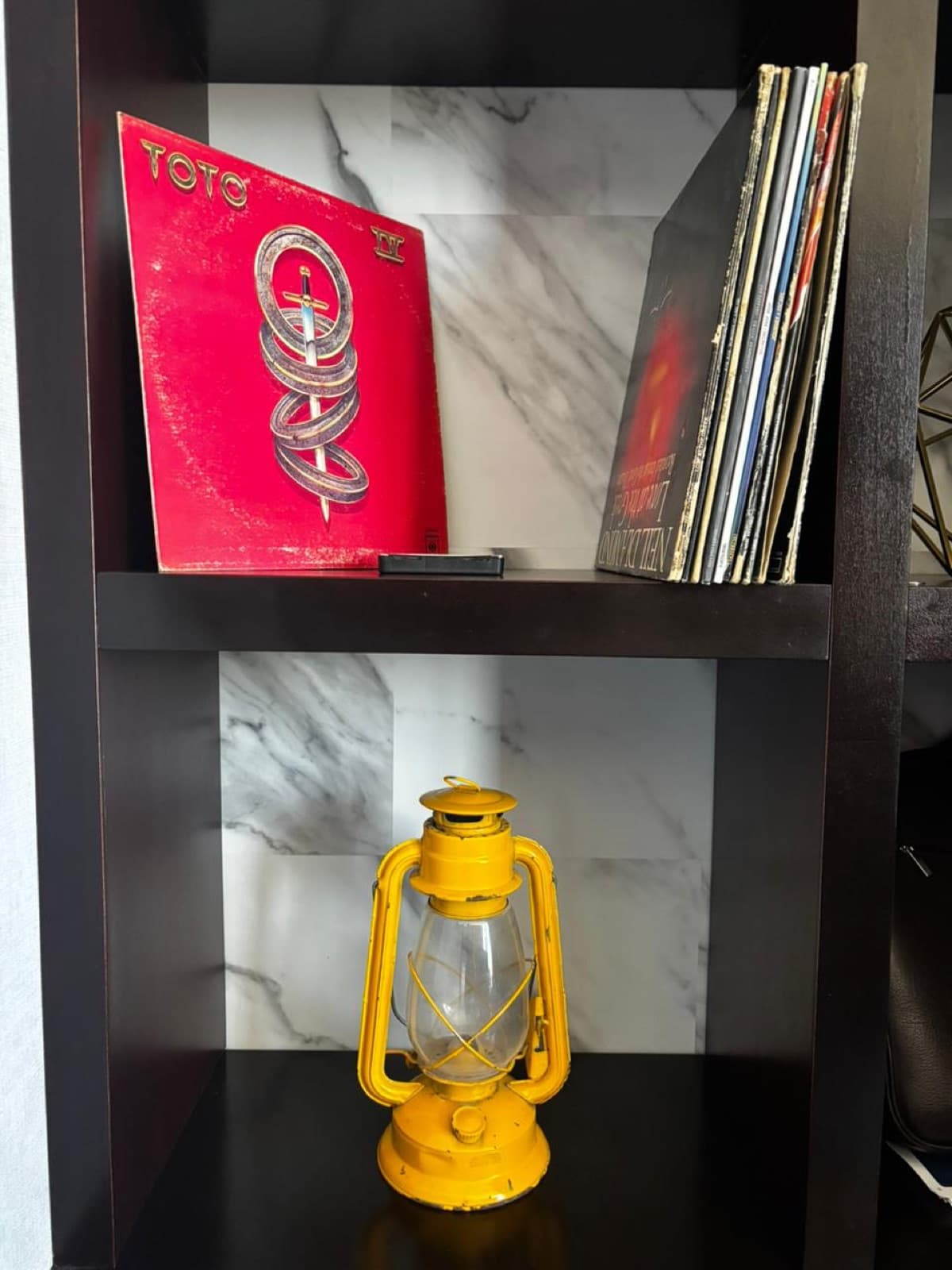 Estantería con libros, vinilo rojo y farol vintage