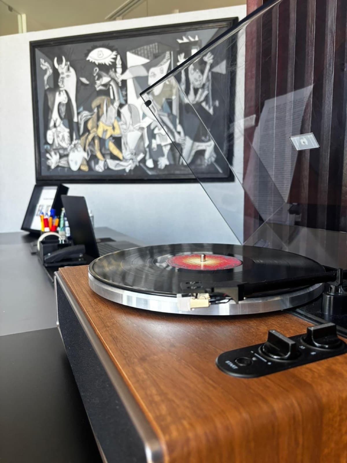 Tocadiscos con vinilo junto a una reproducción del Guernica